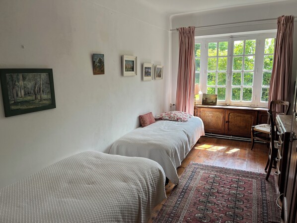 Una camera da letto con due letti, una finestra con tende, una scrivania con sedia e un tappeto.
