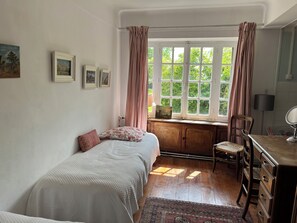 A bedroom with a bed, a desk, a chair, and a window with curtains.