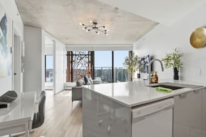 Eine moderne Küche mit Kochinsel, integriertem Geschirrspüler und einem großen Fenster mit Blick auf die Stadt.