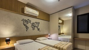 Une chambre d’hôtel avec deux lits, un climatiseur fixé au mur, une décoration murale représentant une carte du monde, une lampe de chevet et un miroir.
