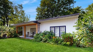 Une maison de plain-pied dotée d’un porche couvert, d’un petit patio et d’un jardin bien entretenu.