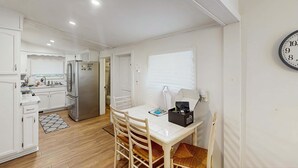 Une cuisine de taille réduite, avec des meubles blancs, un réfrigérateur et un coin repas comprenant une table et des chaises.