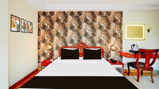 Ein Hotelzimmer mit Wandverkleidung, einem Bett mit schwarzen Kissen, einem Schreibtisch mit Stuhl und einem Nachttisch mit Lampe.