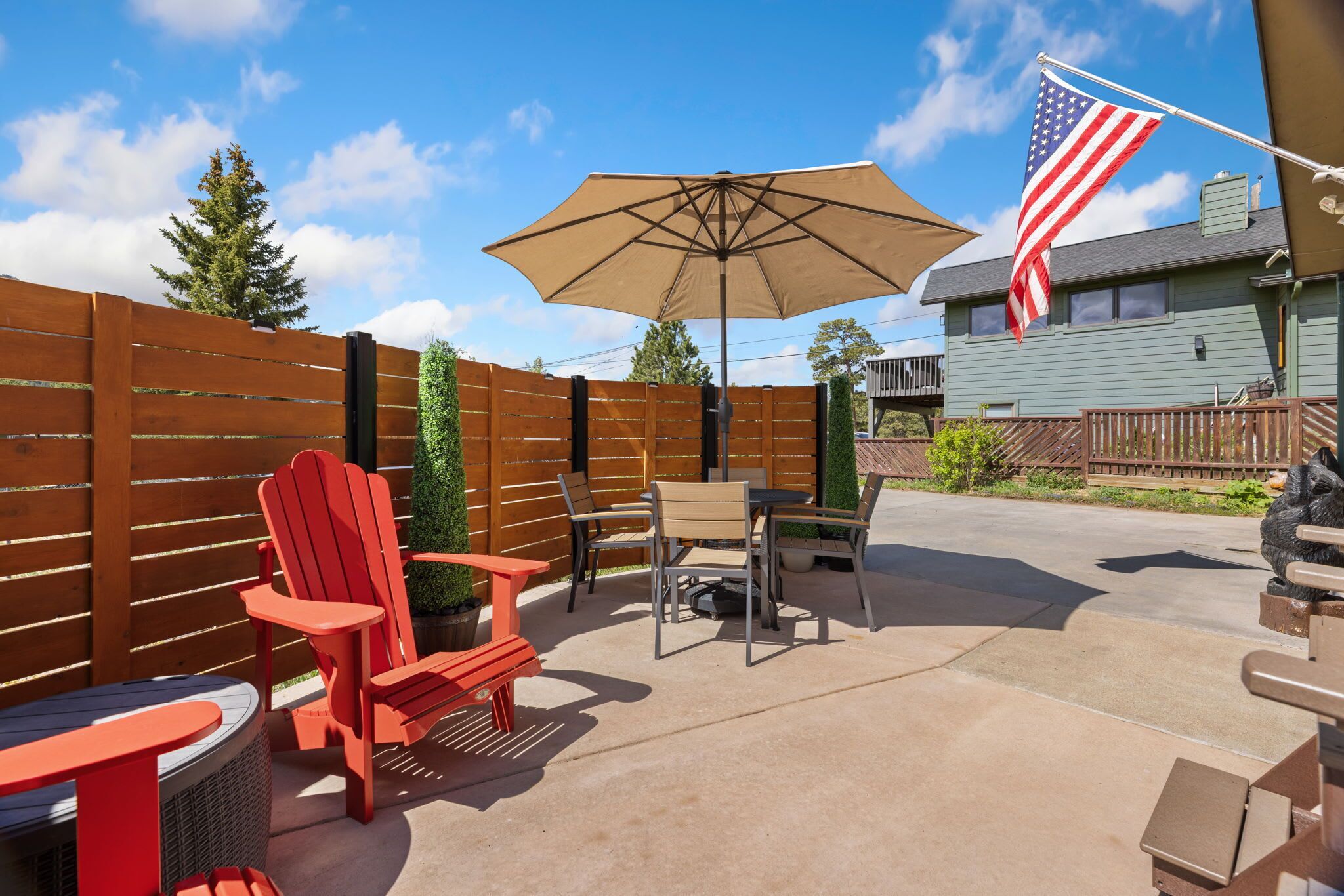 An outdoor patio with a table, chairs, an umbrella, and a flag.