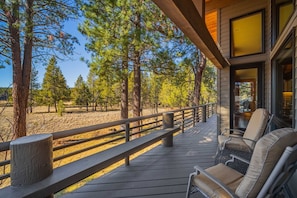 A wooden deck with outdoor furniture, overlooking a forested area. - Spacious 4bd/4bath Riverfront Retreat in Sunriver (Sunriver)