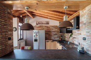 A kitchen with exposed brick walls, wooden beams, and pendant lighting. - "Sunrise over the sea and relaxation on Etna: Green oasis near the pearls of Sicily. (Sicilia)