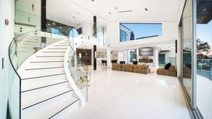 A modern interior with a glass staircase, a living area with sofas, and a large skylight.