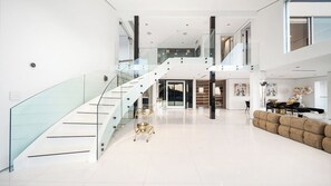 A spacious, modern interior with a glass staircase, a plush sofa, and a dining area.