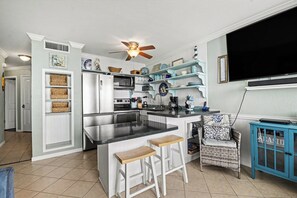 A kitchen with a central island, white cabinetry, and a ceiling fan. - Beachfront condo at Seascape w/view from over-sized balcony with w/d in unit (Galveston)
