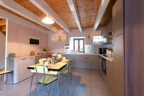 Une cuisine moderne avec des poutres en bois, un coin repas avec des chaises et une petite table.