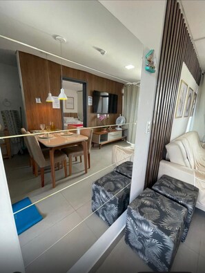 Ein modernes Wohnzimmer mit einer Couch, einem Esstisch und einem Fernseher.