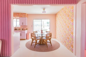 A room with a dining table, chairs, a window, and a door.