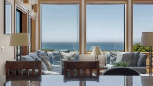 Ein Zimmer mit einem großen Fenster, einem Sofa, einem Tisch und einer Lampe.