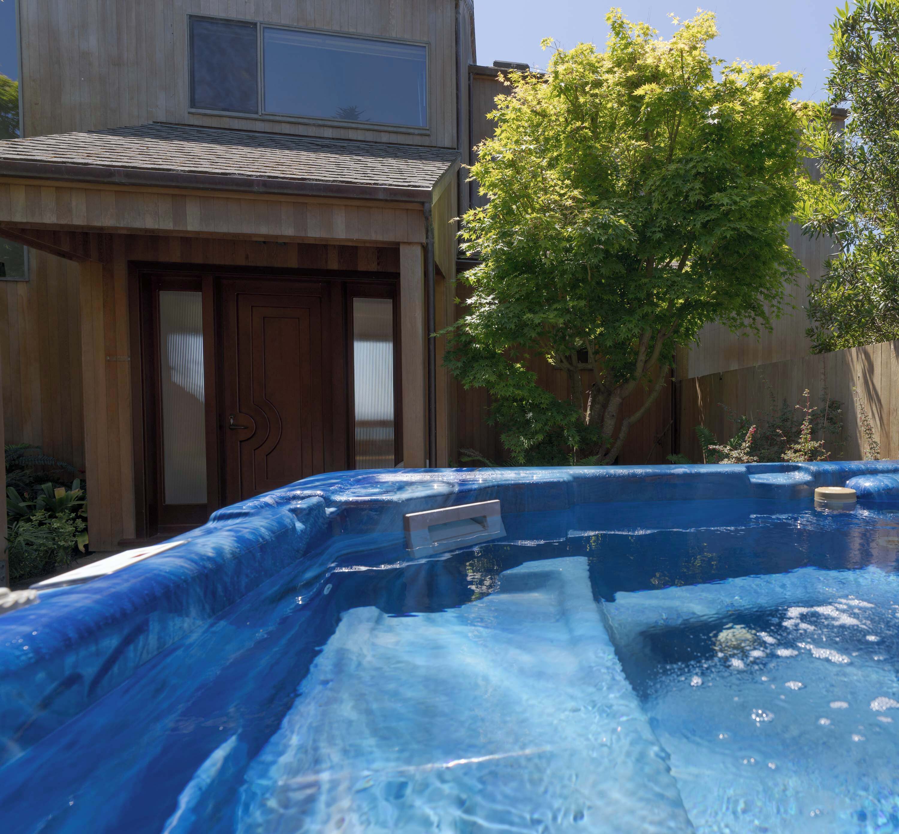 Una piscina amb tobogan, una casa de fusta i un arbre.