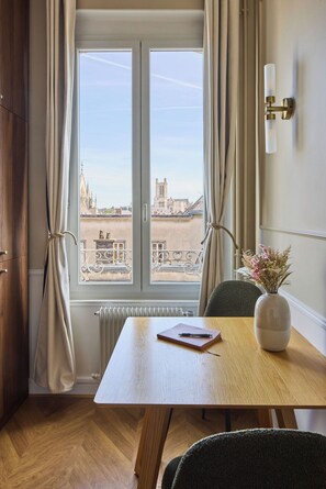 A room with a large window, a table with a notebook and pen, a vase with flowers, and a radiator. - Le Carrousel - Haussmann hyper-centre Troyes - Quiet and rooftop views (Troyes)