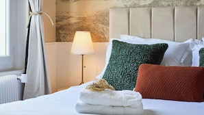 A neatly made bed with a headboard, a lamp, and a wall with a forest mural. - Le Carrousel - Haussmann hyper-centre Troyes - Quiet and rooftop views (Troyes)