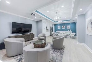 Un salon moderne doté d’un téléviseur à écran plat, d’un canapé, d’une table basse et d’un coin repas avec une table et des chaises.