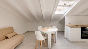 A modern loft-style room with a dining area, a sofa, and a kitchen. - Brand new Attic Studio Apartment, air Conditioned (Castelsardo)