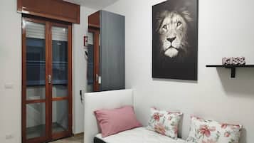 Un dormitorio con cama, una puerta, un cuadro en la pared y una estantería.