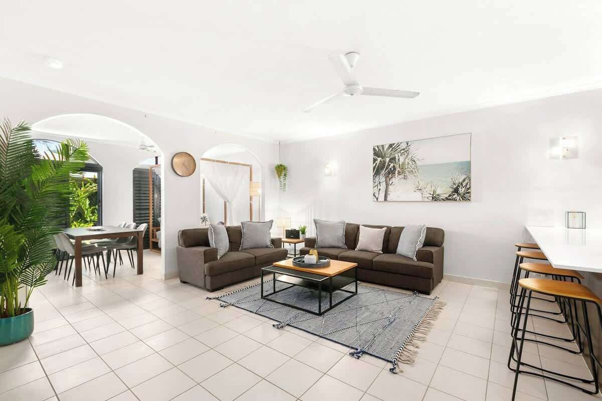 A modern living room with a sofa set, a coffee table, a dining area, and a large window.