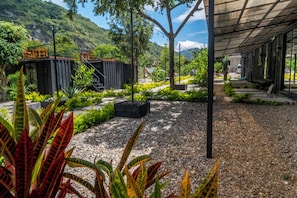 A landscaped outdoor area with gravel paths, potted plants, and a view of a mountainous landscape. - STEELCRAFT HOTEL (Panajachel)
