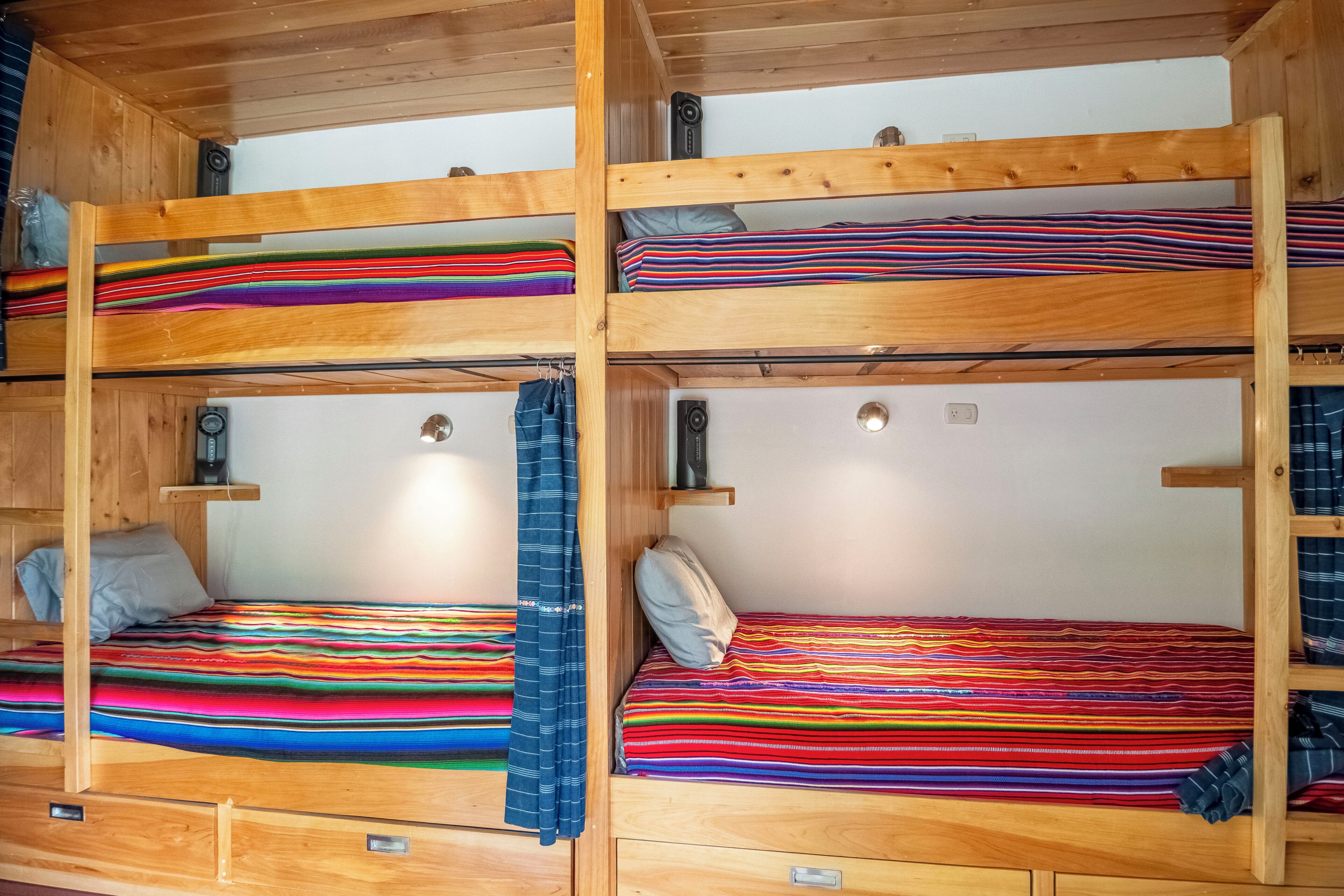 Une chambre avec des lits superposés, comprenant plusieurs lits, chacun étant agrémenté de draps rayés aux couleurs vives.