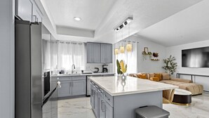 Cocina moderna con gabinetes grises, encimera de mármol y una isla central.