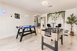 A room with two foosball tables, a neon sign, and a plant. - Spacious 7BR/5BA 8 Beds w/Hot Tub | Near & Airport (Las Vegas)