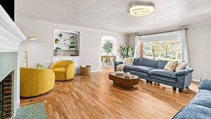 Ein Wohnzimmer mit Kamin, einem gelben Sessel, einem blauen Sofa und einem Couchtisch aus Holz.