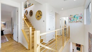 A modern interior with a wooden staircase, white walls, and various artworks. - Silverlake Sunset Treehouse Art-filled Escape w/ Jacuzzi + Sauna Avantstay (Los Angeles)