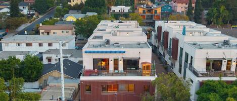 A residential area with modern buildings, including a house with a visible balcony and a building with solar panels.