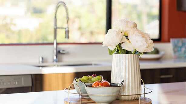 A kitchen counter with a vase of flowers, a bowl of fruit, and a sink. - Silverlake Sunset Treehouse Art-filled Escape w/ Jacuzzi + Sauna Avantstay (Los Angeles)