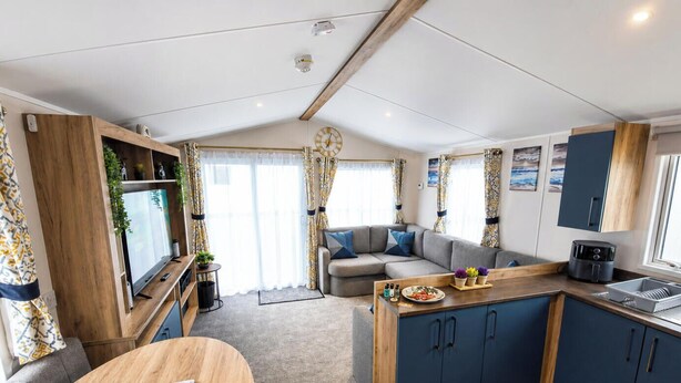 Ett kompakt bostadsutrymme med ett litet kök, en soffa, ett matbord och en TV.