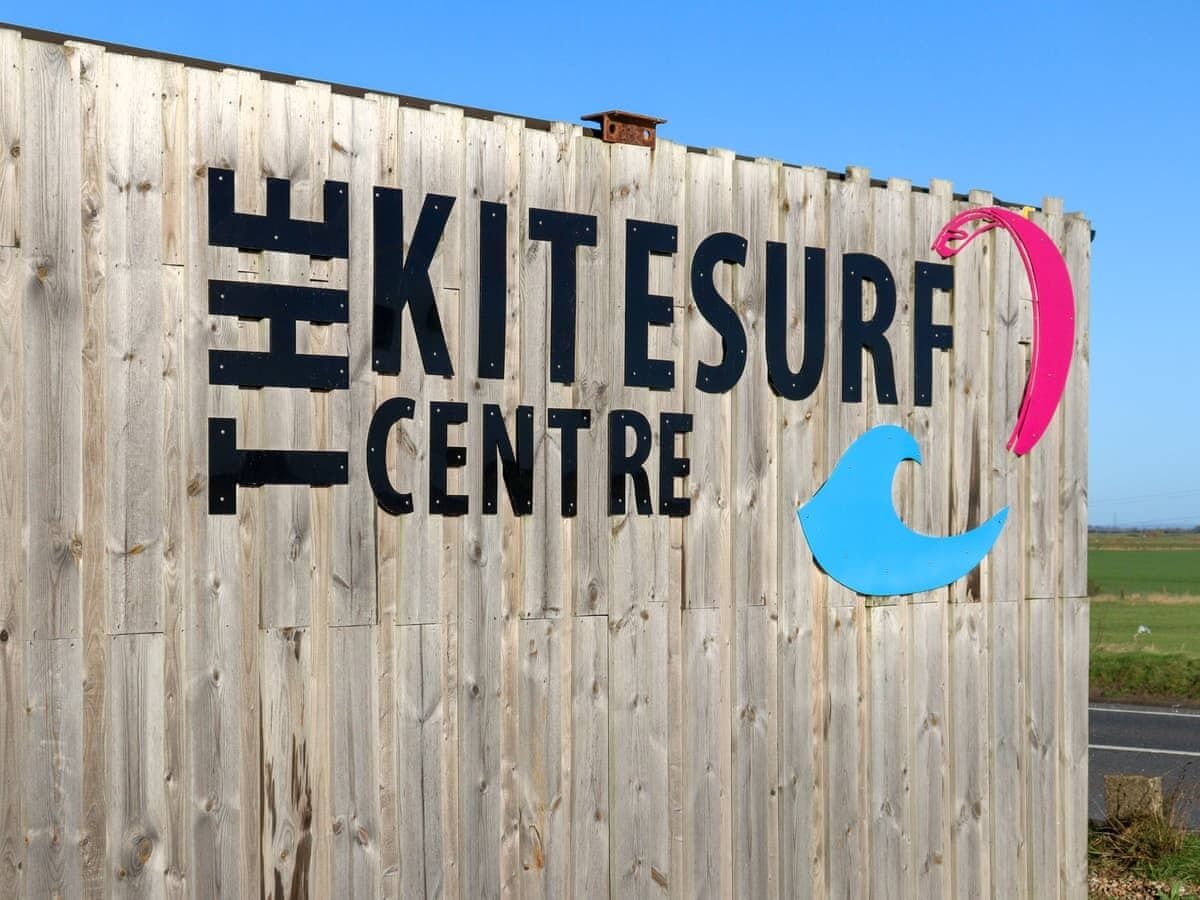 A wooden sign with 'The Kitesurf Centre' written on it.