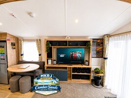 Una sala de estar moderna con un televisor de pantalla plana, muebles de madera y un letrero de MKRJ Rentals.