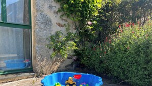 Uma piscina infantil azul de plástico cheia de brinquedos e um pequeno veículo amarelo de brinquedo em um deck de madeira.