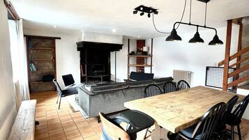 A dining area with a wooden table and chairs, a bench, a fireplace, and a staircase.