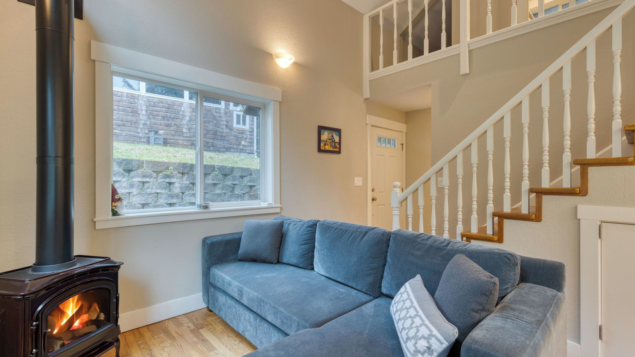 Un salon avec un canapé, une cheminée, une fenêtre et un escalier.