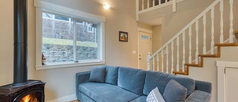 Un salon avec un canapé, une cheminée, une fenêtre et un escalier.