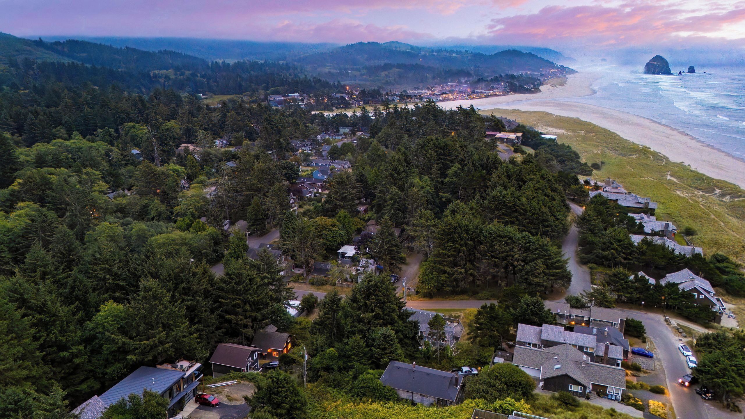 Vue aérienne d’une zone résidentielle côtière, avec des maisons, des routes et une plage.