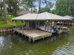 A docked boat with a covered seating area, a picnic table, and a ladder leading to the dock. - Welcome to Lake Blessing 2026 (Frankston)