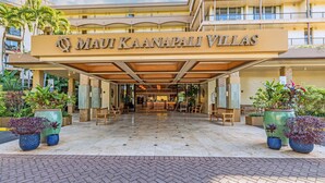 Ein Hotel Eingang mit Namensschild, Sitzgelegenheiten im Freien und Blumentöpfen.