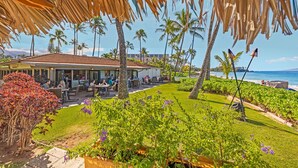Ein Restaurant mit Außenbereich, Palmen und Blick auf das Meer.