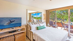 Ein Hotelzimmer mit Bett, Fernseher, Deckenventilator und einem Balkon mit Blick.