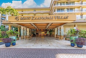 A hotel entrance with a name sign, outdoor seating, and potted plants. - Beachfront Ka'anapali Studio - Vacation West Maui (Lahaina)