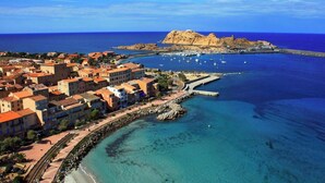 An aerial view of a coastal town with buildings, a rocky island, and clear blue waters. - Casa Mare Lina Île rousse - T3 old town 1 min from the beach (L'Île-Rousse)