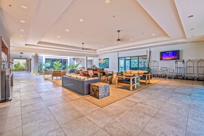 A spacious lobby with a high ceiling, modern furniture, and a large screen displaying information. - Valley Isle Resort #506 - Vacation West Maui (Lahaina)