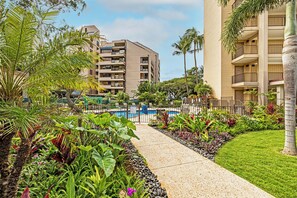 A hotel with a pool, lush greenery, and a clear sky. - Valley Isle Resort #506 - Vacation West Maui (Lahaina)
