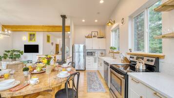 A modern kitchen with a central island, stainless steel appliances, and a large window.