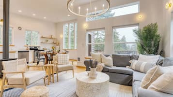 A spacious living room with a fireplace, a dining area, and large windows offering a view of the outdoors.